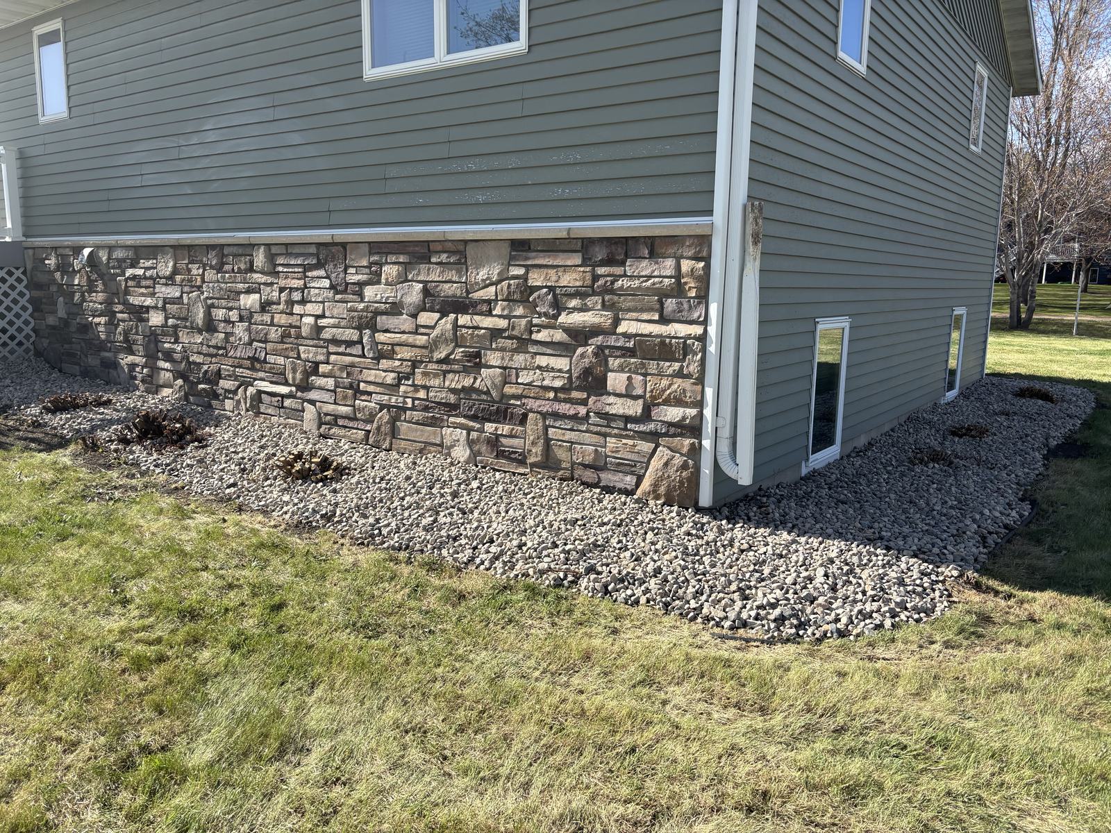 River rock landscaping along a stone foundation